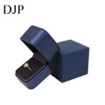 Navy blue ring box with a diamond ring inside and matching outer box